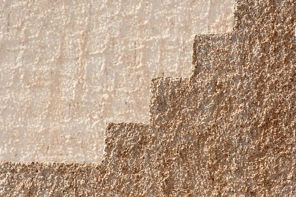 Close-up of a textured cement wall featuring a step-like pattern creating a rustic look.